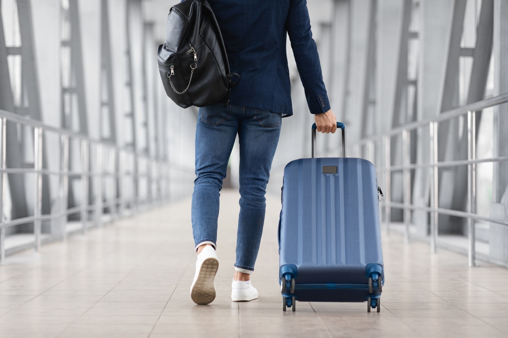 Man With Bag And Suitcase Walking In Airport Terminal